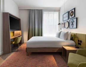 King bedroom with mini fridge, sofa and TV screen at the Hampton by Hilton London Ealing.