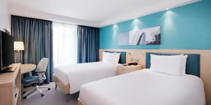 Twin room with TV screen and desk at the Hampton by Hilton Bristol Airport.