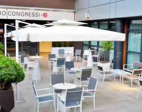 Outdoor terrace with sun umbrellas, chairs and tables at the Hilton Garden Inn Milan North.