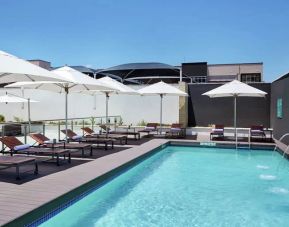 Narrow rectangular pool with fountains coming out of side wall, abundant lounge chairs for sunbathing.