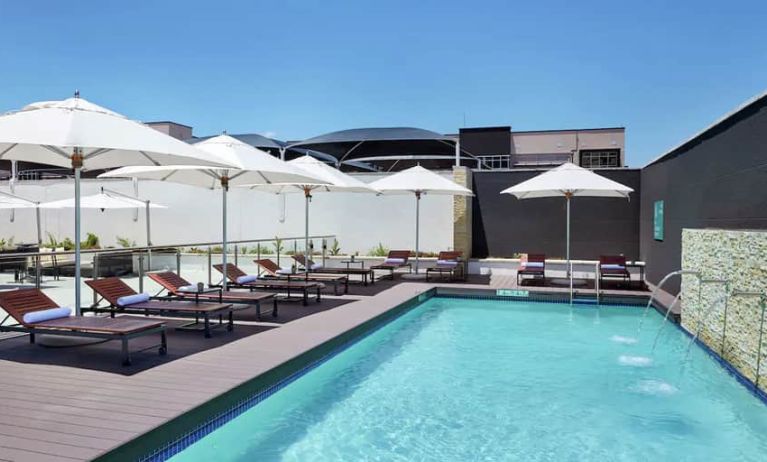 Narrow rectangular pool with fountains coming out of side wall, abundant lounge chairs for sunbathing.