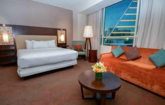 King bedroom with window and sofa at the Hilton Dallas Plano Granite Park.