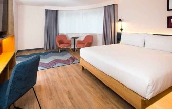 cosy king room with TV, desk, and lounge area ideal for working remotely at Hampton by Hilton London Park Royal.
