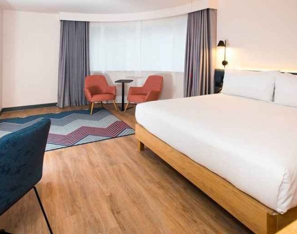 cosy king room with TV, desk, and lounge area ideal for working remotely at Hampton by Hilton London Park Royal.