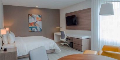 luxurious king suite with TV, work desk, and dining area at Hilton Garden Inn Santa Ana San Jose.