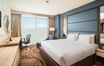 comfortable king room with TV, work desk, and natural light at Hilton Garden Inn Bogota Airport.