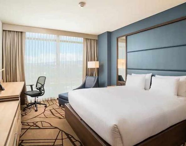 comfortable king room with TV, work desk, and natural light at Hilton Garden Inn Bogota Airport.