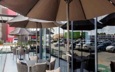 Outdoor terrace with chairs, tables and sun umbrellas at the Hampton Inn by Hilton Cancun Cumbres.