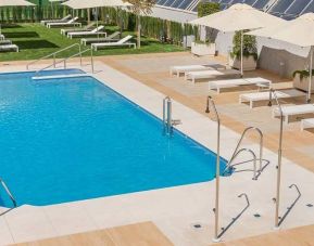 stunning outdoor pool with sun beds and umbrellas at Hilton Garden Inn Sevilla.