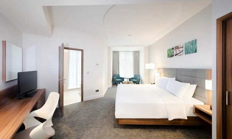 spacious king room with TV, desk, chair, and lots of natural light at Hilton Garden Inn Bucharest Old Town.