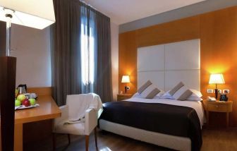 comfortable king suite with table, chair, and TV at Hilton Garden Inn Milan Malpensa.