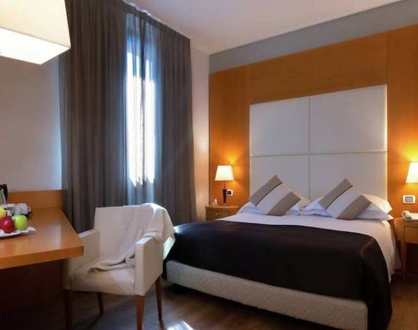 comfortable king suite with table, chair, and TV at Hilton Garden Inn Milan Malpensa.