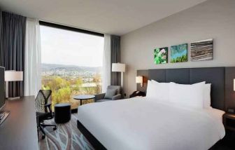 Bright king bedroom with desk along the window at the Hilton Garden Inn Zurich Limmattal.