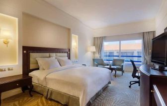 lovely king suite with TV, lounge area, work desk, and chair at Hilton Alexandria Green Plaza.