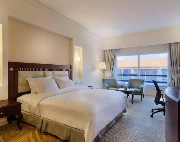 lovely king suite with TV, lounge area, work desk, and chair at Hilton Alexandria Green Plaza.