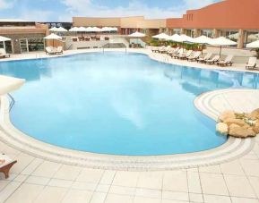 stunning outdoor pool with sunbeds and umbrellas at Hilton Alexandria Green Plaza.