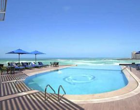 stunning outdoor pool with sunbeds and umbrellas at Hilton Alexandria Corniche.