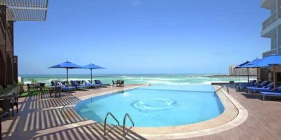 stunning outdoor pool with sunbeds and umbrellas at Hilton Alexandria Corniche.