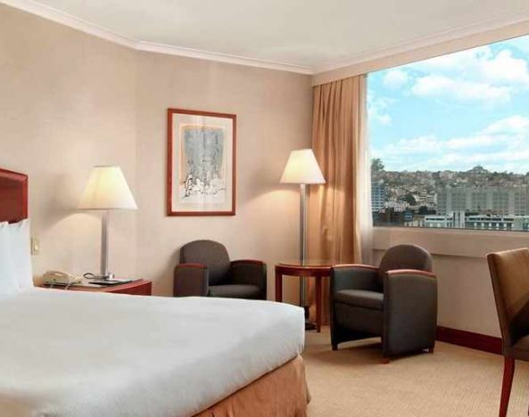 comfortable king room with TV, desk, chair, and couches at Hilton Colon Quito.