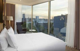 delux king bed with chair and city views at Hilton Tallinn Park.