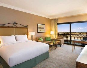 spacious delux king bedroom with TV, desk, chair, and lounge area at Hilton Alexandria King's Ranch.