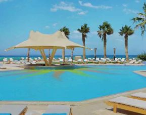 stunning outdoor pool with sunbeds and umbrellas at Hilton Hurghada Plaza.