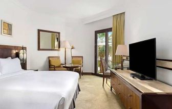 spacious king suite with TV, desk, chair, and dining area at Hilton Luxor Resort & Spa.