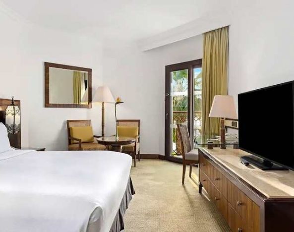 spacious king suite with TV, desk, chair, and dining area at Hilton Luxor Resort & Spa.