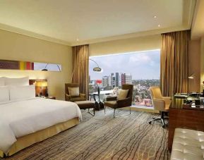 comfortable delux king room with TV, business desk, and lounge area at Hilton Chennai.