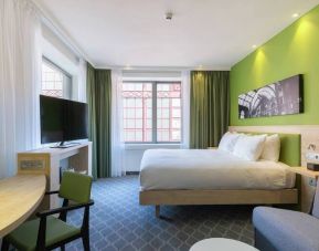Lime green walls and a chic city view complement this king-size bed with workspace and television hotel room.