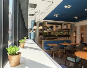 White sunlit table lines window with succulents, other small tables for 1-2 people fill a spacious lobby, perfect for working remotely.