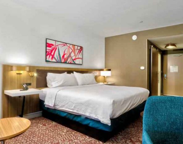 Queen size bed with TV, ottoman, chair and table to sit at Hilton Garden Inn Bel Air.