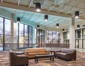 Comfortable lobby and coworking space with lots of natural light at Red Roof PLUS+ & Suites Houston - IAH Airport SW.