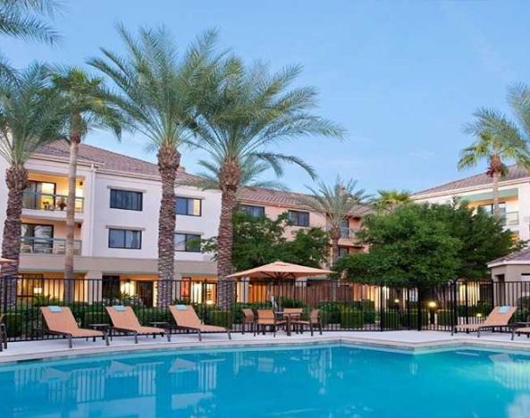 Stunning outdoor pool with sunbeds and pool umbrellas at Sonesta Select Phoenix Chandler.