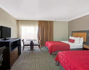 Twin room with desk, TV screen and table at Ramada Los Angeles Downtown West.