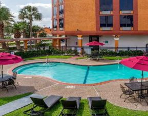 Large outdoor pool with seating area and sun umbrellas at Quality Inn Pasadena.