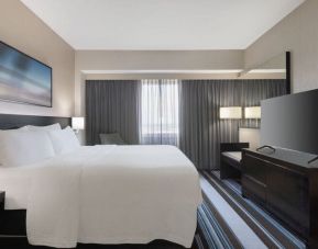 Comfortable king room with TV and couch at Courtyard By Marriott New York JFK Airport.