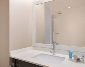Spacious guest bathroom with shower at Courtyard By Marriott New York JFK Airport.
