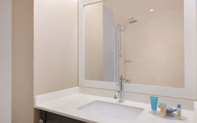 Spacious guest bathroom with shower at Courtyard By Marriott New York JFK Airport.