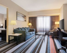 Luxurious king suite with TV, work desk, and couch at Courtyard By Marriott New York JFK Airport.