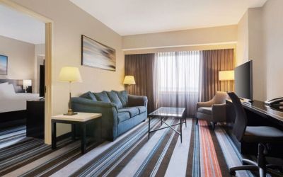 Luxurious king suite with TV, work desk, and couch at Courtyard By Marriott New York JFK Airport.