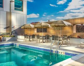 Lovely outdoor pool with sunbeds, seating area, and umbrellas at Hyatt Place Washington D.C/National Mall.