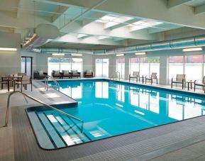 Large indoor pool with surrounding seating area at Courtyard By Marriott Toronto Airport.