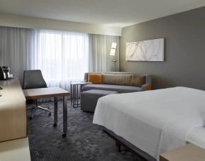 Comfortable king bedroom with TV, work station, and couch at Courtyard By Marriott Toronto Airport.