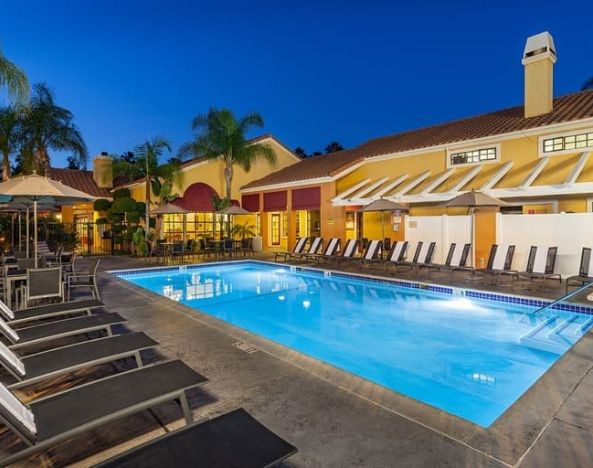 Stunning outdoor pool with sunbeds and umbrellas at Clementine Hotel & Suites Anaheim.