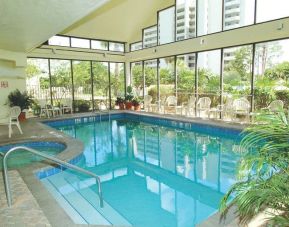 Lovely indoor pool with seating area at Enclave Suites by Sky Hotels & Resorts.