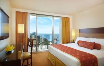 Spacious king bedroom with sea view, balcony, and business desk at Park Shore Waikiki.