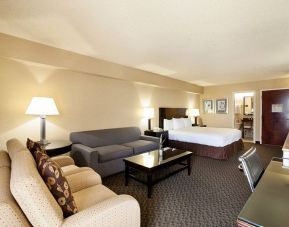 Junior suite of the Radisson Hotel JFK Airport, with bed and pair of sofas, plus small table.