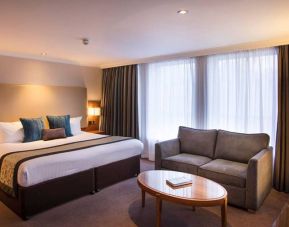 Wide view of the junior suite double room, with small sofa, coffee table, and spacious bed.