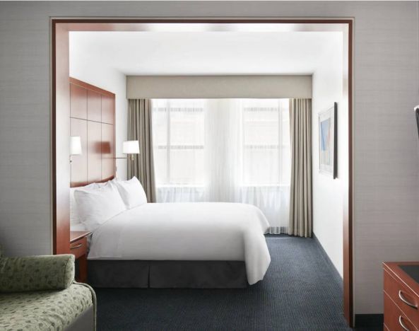 One of the Club Quarters Hotel Central Loop’s guest rooms, featuring bed, chair, and window.